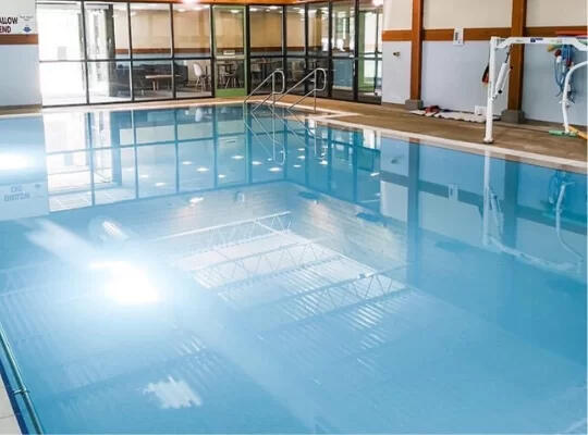 Pool For Hydrotherapy Indoor therapeutic swimming pool with lane markings in a modern hydrotherapy facility, featuring natural lighting and professional coaching areas